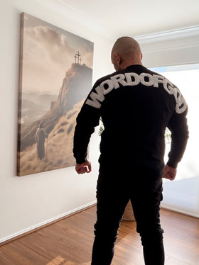 Man wearing a black WORDOFGOD crew neck jumper, back view of arched WORDOFGOD print | WORDOFGOD Apparel
