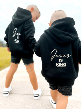 Two kids wearing black Jesus Is King hoodies, back view | WORDOFGOD Apparel